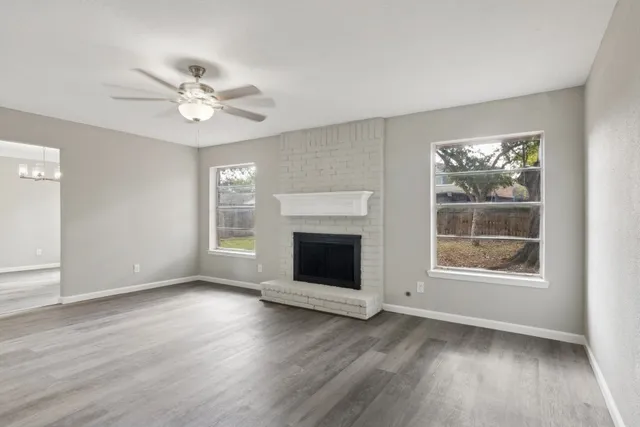 an empty room with wooden floor a ceiling fan and windows