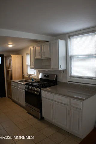 a kitchen with stainless steel appliances granite countertop a stove a sink and white cabinets
