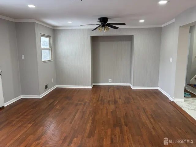 a view of empty room with wooden floor and fan