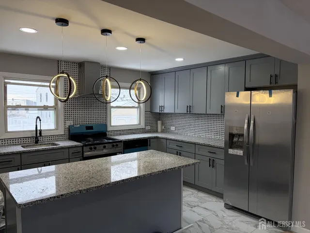 a kitchen with granite countertop a sink a stove and refrigerator