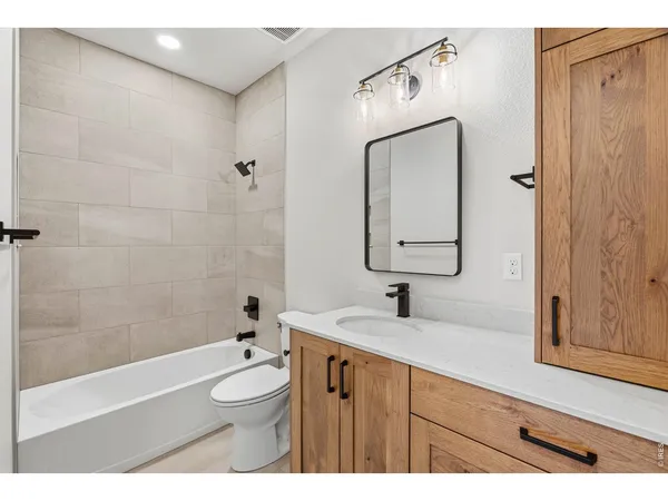 a bathroom with a double vanity sink toilet mirror and shower