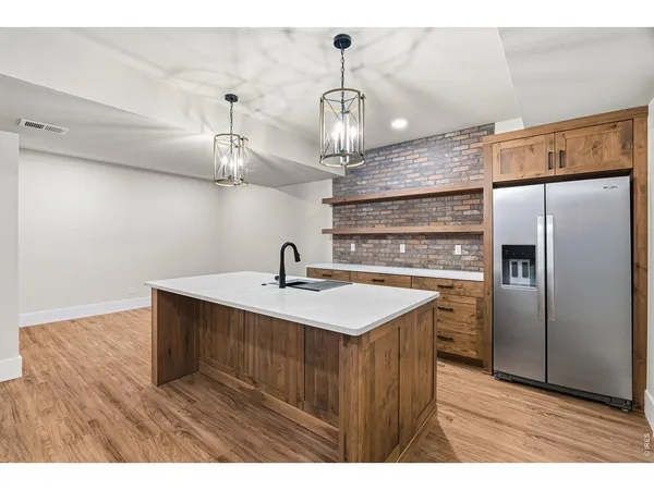 a kitchen with stainless steel appliances a sink a refrigerator a center island and wooden floor