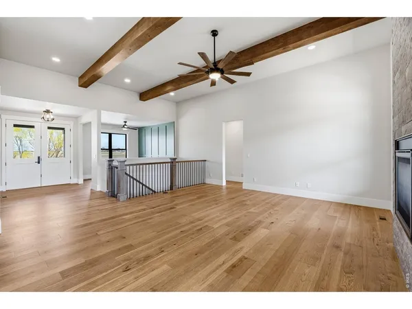 a view of an empty room with window and wooden floor