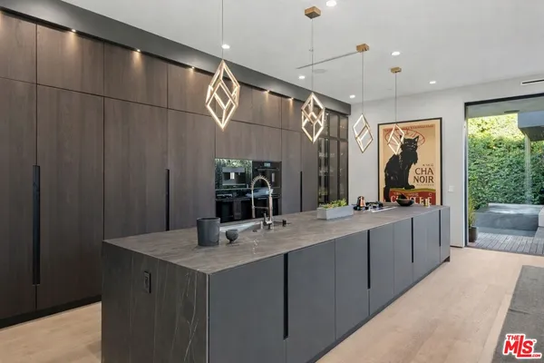 a large kitchen with a large counter space a sink stainless steel appliances and cabinets