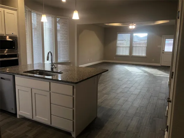 a kitchen with stainless steel appliances granite countertop a refrigerator a stove and a sink with wooden floor