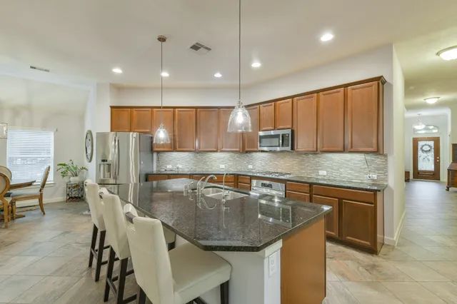 a kitchen with kitchen island granite countertop a sink stove and cabinets