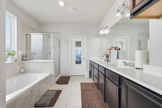 a bathroom with a tub a sink and a large mirror