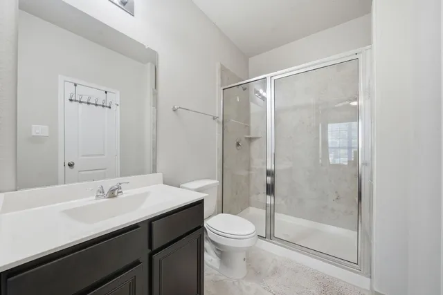 a bathroom with a shower sink vanity mirror and toilet