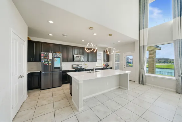 a large kitchen with a large counter top stainless steel appliances lots of counter top space cabinets and a potted plant