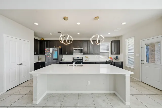 a large kitchen with a large counter top stainless steel appliances and cabinets