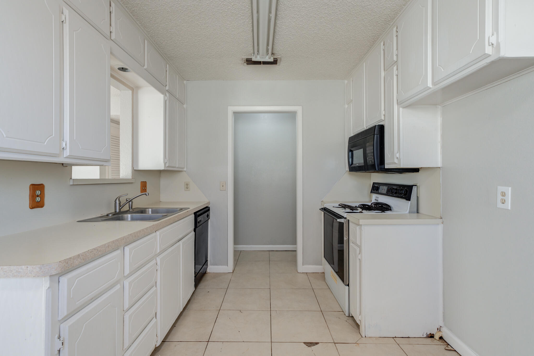 6212 22nd Street Lubbock, TX 79407 - Photo 10 of 24 a kitchen with a sink a stove top oven and white cabinets
