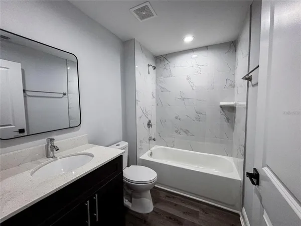 a bathroom with a granite countertop sink a toilet and shower