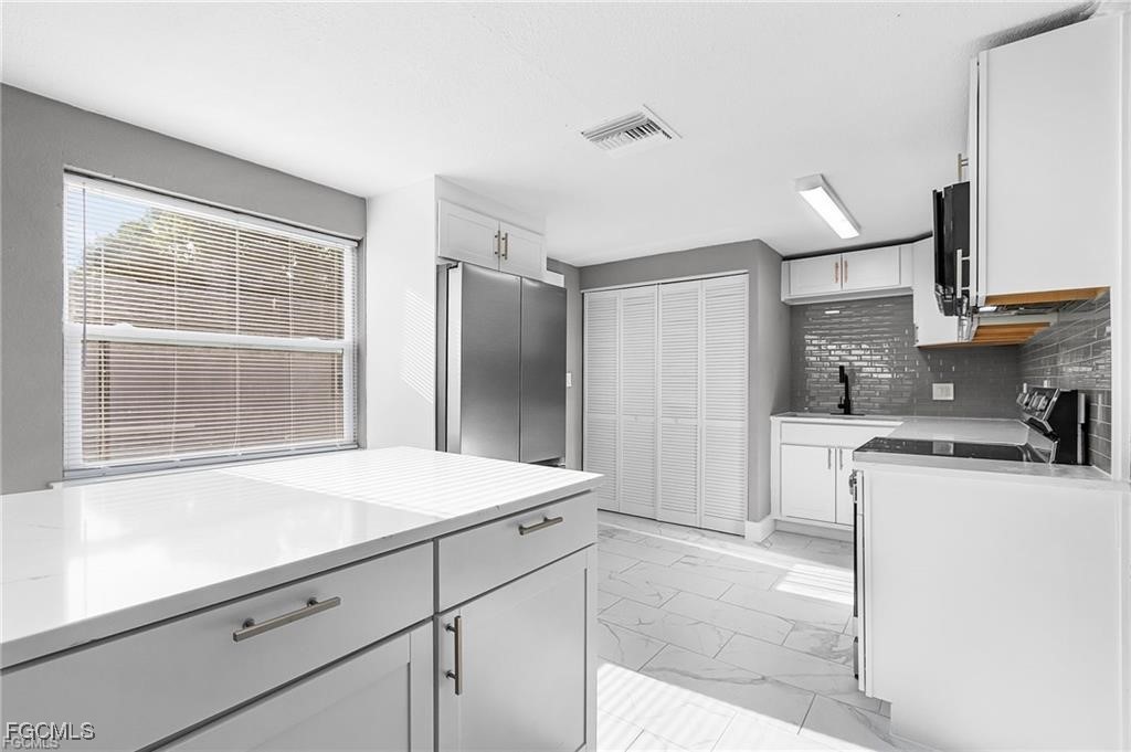 4472 East Riverside Drive Fort Myers, FL 33905 - Photo 14 of 17 a kitchen with stainless steel appliances kitchen island granite countertop a refrigerator and a sink