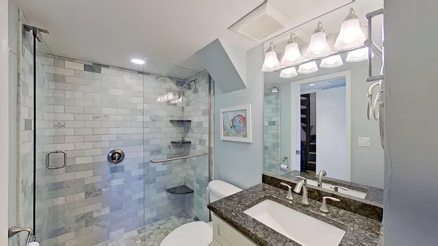 a bathroom with a granite countertop sink toilet a mirror a glass door shower and a mirror