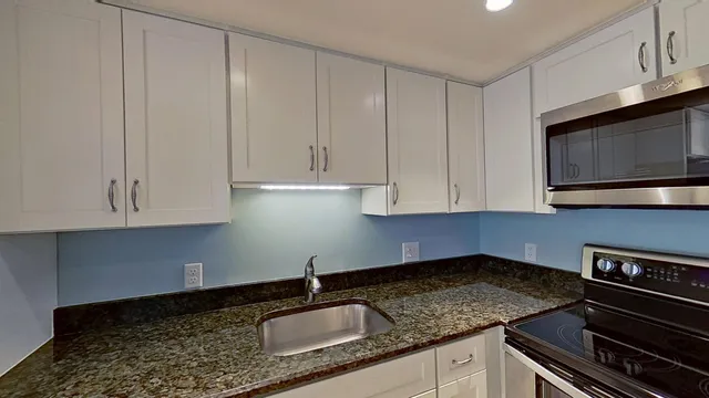 a kitchen with granite countertop white cabinets and sink