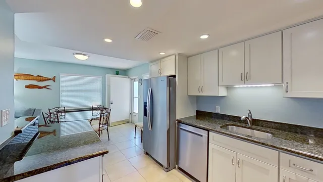 a kitchen with granite countertop a refrigerator a sink a stove a dining table and chairs