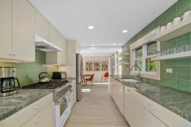 a large kitchen with stainless steel appliances granite countertop a lot of counter space and a sink