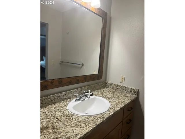 a bathroom with a granite countertop sink and a mirror