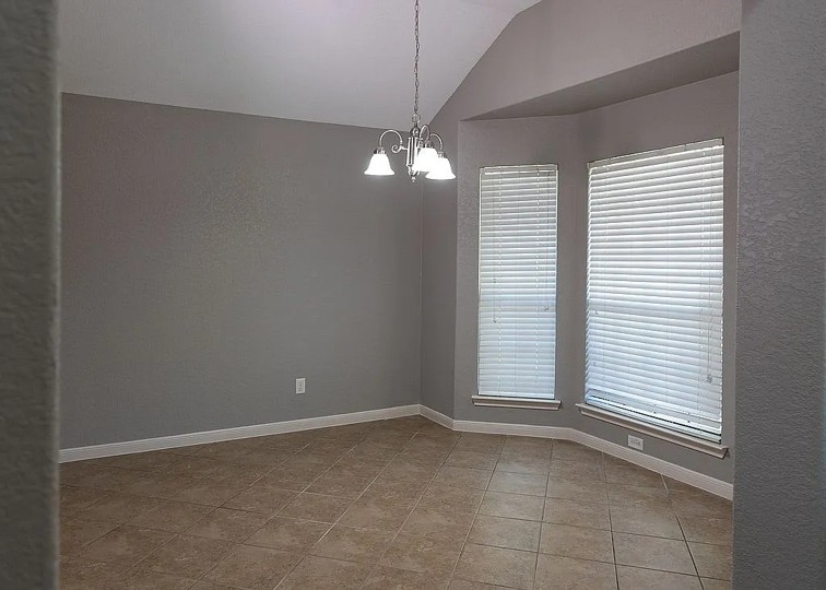 7703 Redstone Manor Converse, TX 78109 - Photo 2 of 28 Tiled empty room featuring suspended lighting, lofted ceiling, and a textured wall