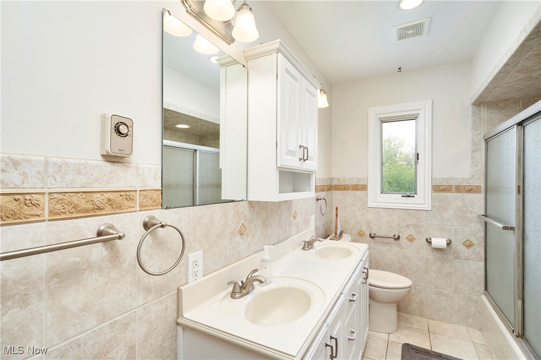 2530 Holgate Road Akron, OH 44313 - Photo 18 of 31 Bathroom with tile walls, tile patterned flooring, double vanity, toilet, and wainscoting