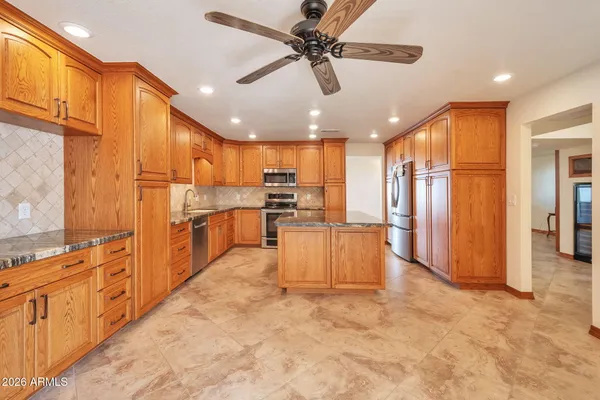 a view of an empty room with wooden floor and a ceiling fan