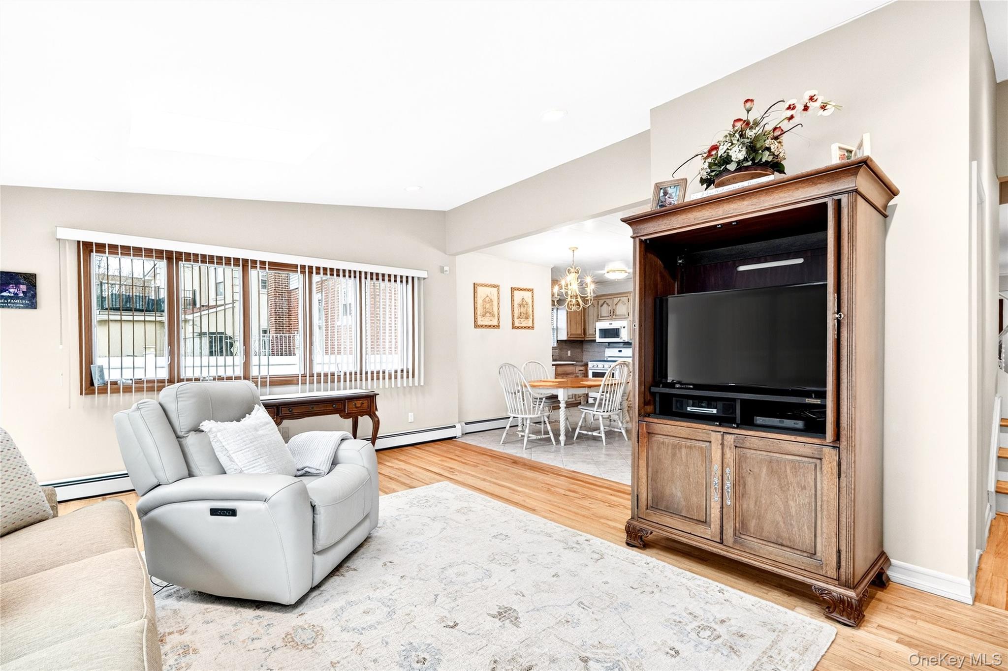 3334 Country Club Road Bronx, NY 10465 - Photo 26 of 49 Living room featuring vaulted ceiling, a chandelier, light wood-type flooring, a baseboard heating unit, and a baseboard radiator