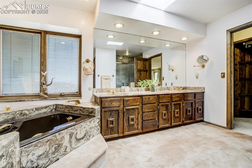 7035 Switchback Trail Colorado Springs, CO 80919 - Photo 17 of 45 a spacious bathroom with a granite countertop double vanity sink a mirror and a bathtub