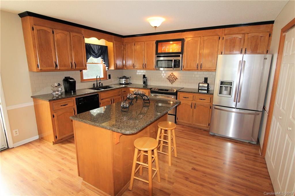 827 Brian Road, Unit 5 Clover, SC 29710 - Photo 3 of 21 a kitchen with stainless steel appliances granite countertop a refrigerator a stove a sink dishwasher and microwave with wooden floor