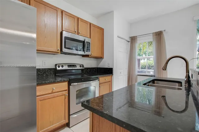 a kitchen with granite countertop a sink stainless steel appliances and cabinets