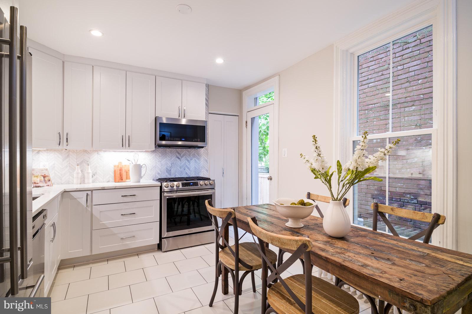 1833 12th Street Northwest Washington, DC 20009 - Photo 12 of 30 a kitchen with stainless steel appliances granite countertop a stove top oven a dining table and chairs with wooden floor