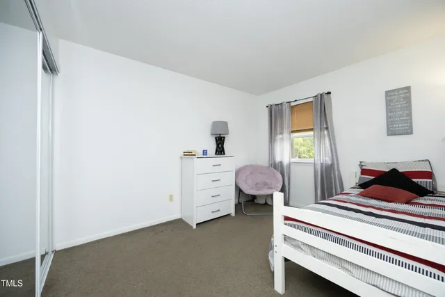 a bedroom with a bed and a flat tv screen on dresser