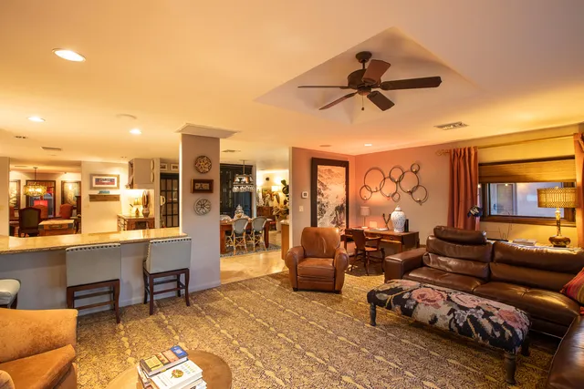 a dining hall with stainless steel appliances kitchen island granite countertop a sink and chairs