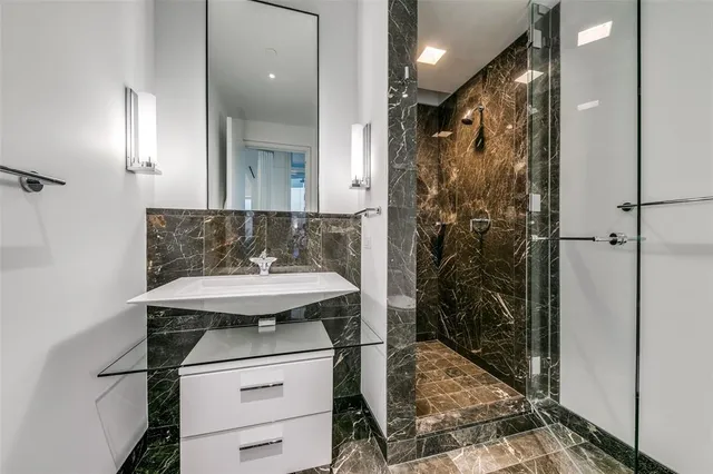 a bathroom with a sink shower and a mirror