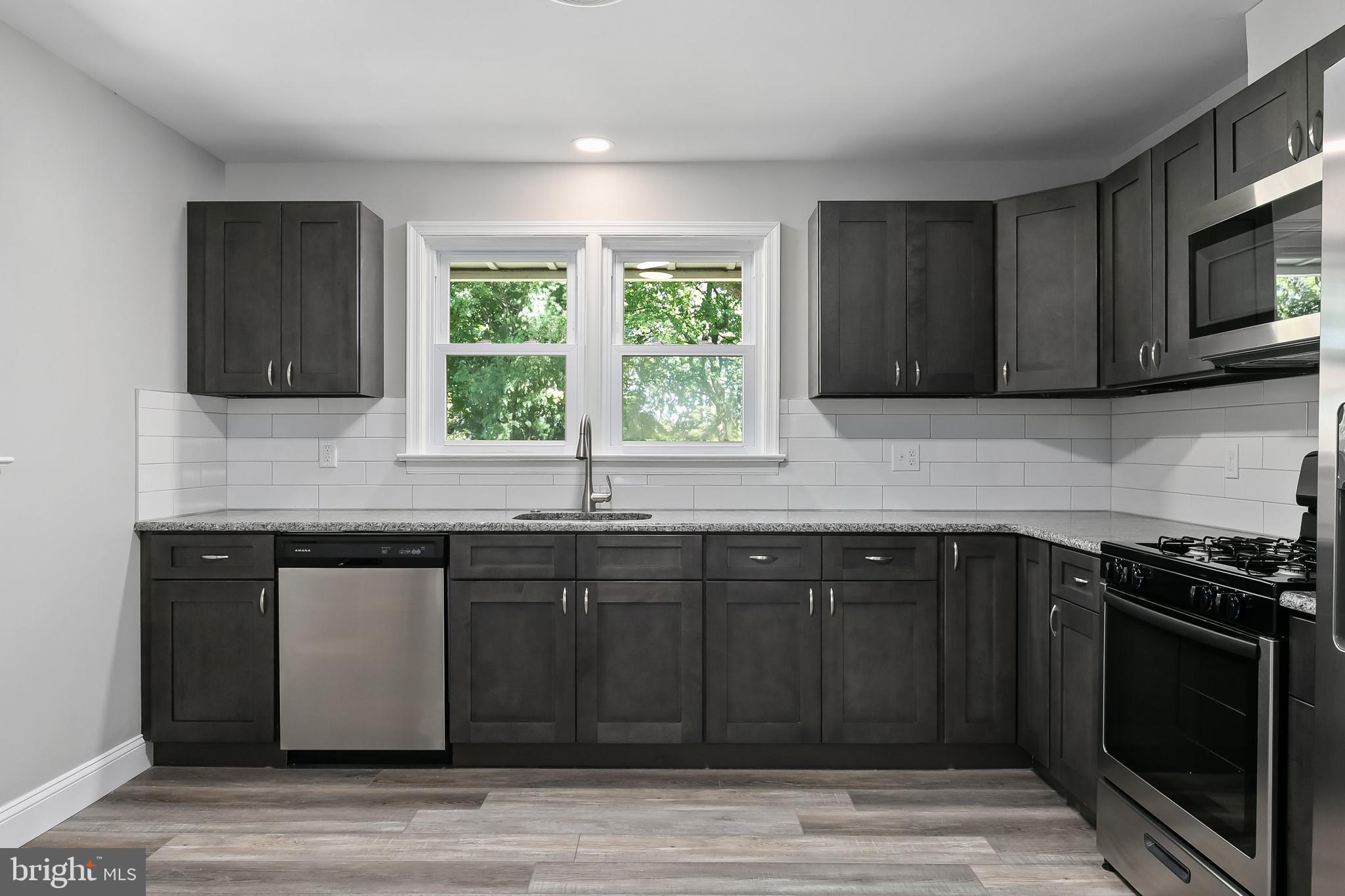 405 Hamilton Road Glassboro, NJ 08028 - Photo 8 of 28 a kitchen with granite countertop a stove a sink and a microwave