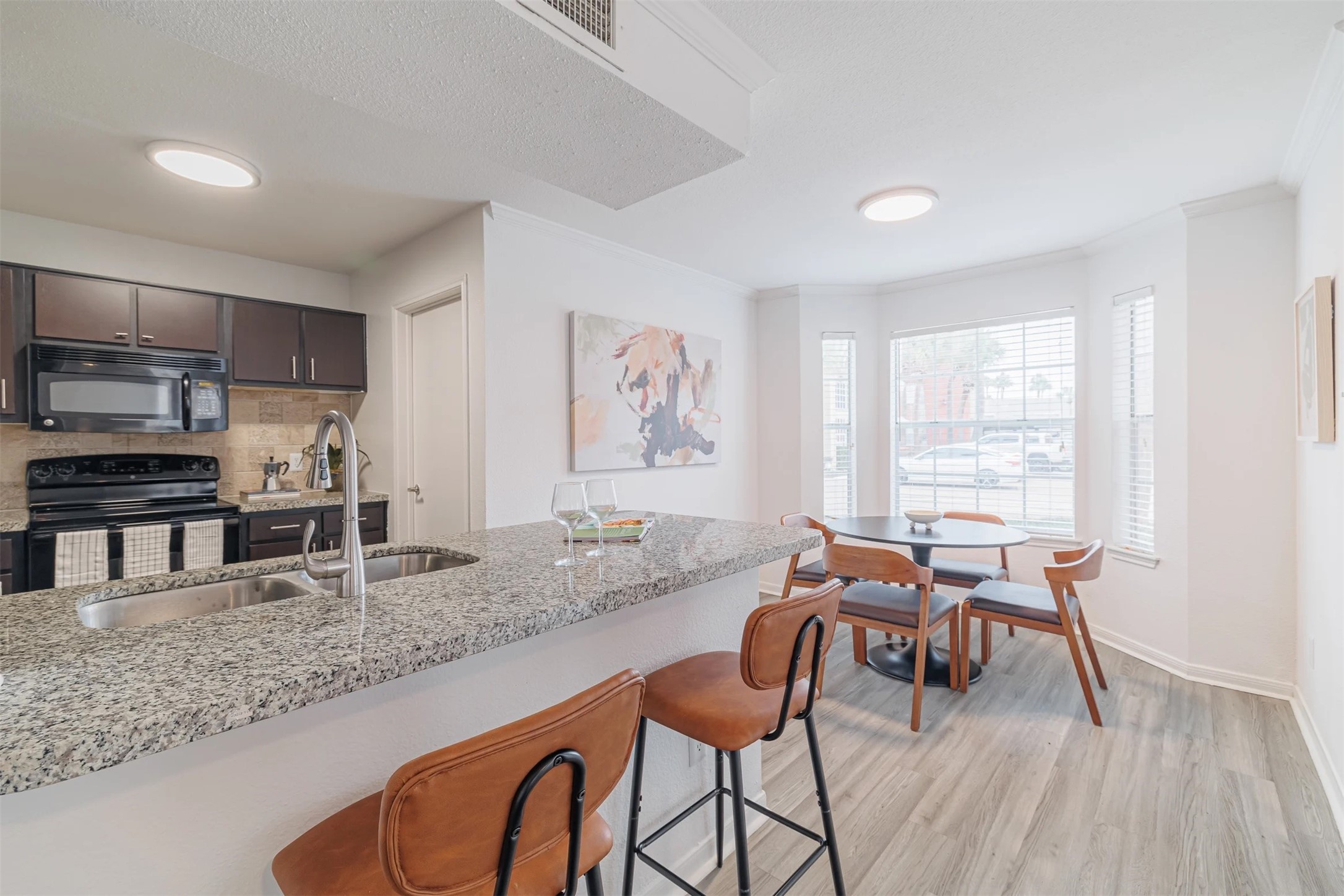 8300 El Mundo Street, Unit 192 Houston, TX 77054 - Photo 4 of 27 a kitchen with stainless steel appliances granite countertop a stove top oven a sink a dining table and chairs with wooden floor