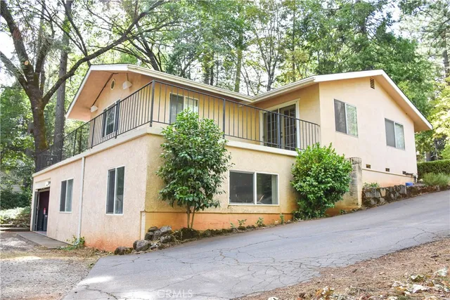 a aerial view of a house with yard and trees in the background