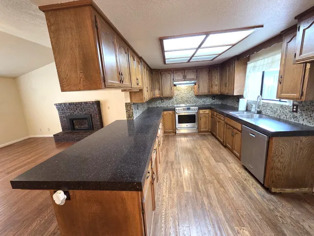 a large kitchen with a stove a sink dishwasher a microwave oven and a dining table with wooden floor