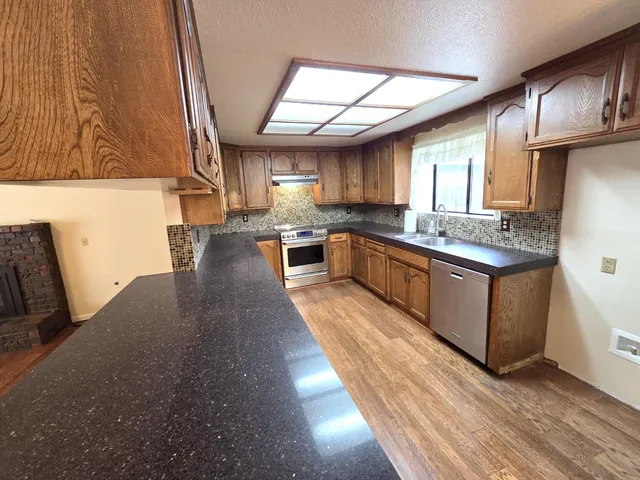a large kitchen with stainless steel appliances granite countertop a lot of counter space and a window
