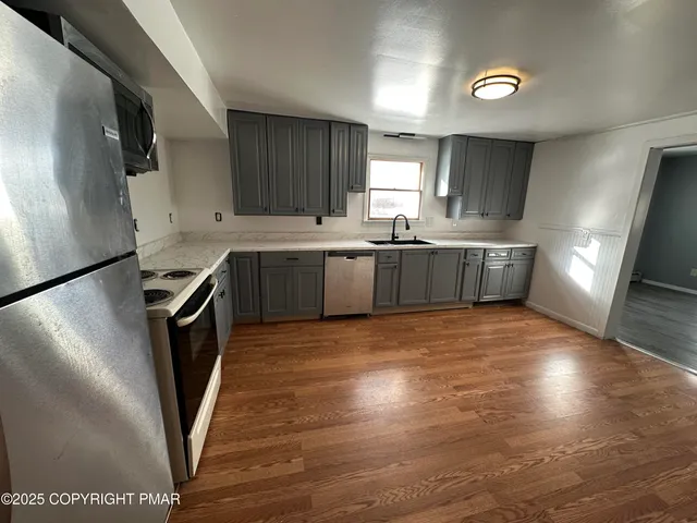 a large kitchen with stainless steel appliances granite countertop a stove a sink and a refrigerator