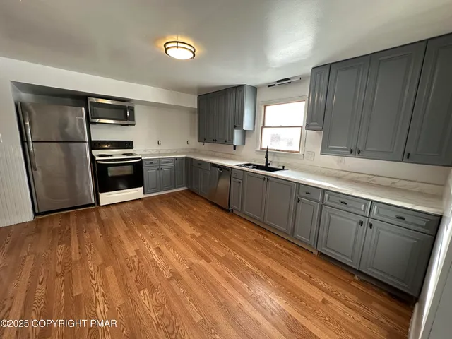 a kitchen with stainless steel appliances granite countertop a sink a stove and refrigerator