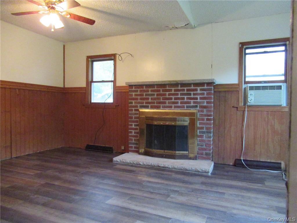 357 Mountain Lodge Road Monroe, NY 10950 - Photo 2 of 20 Unfurnished living room featuring a textured ceiling, dark wood-type flooring, ceiling fan, a fireplace, and cooling unit