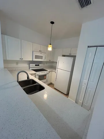 a kitchen with a sink a refrigerator and cabinets