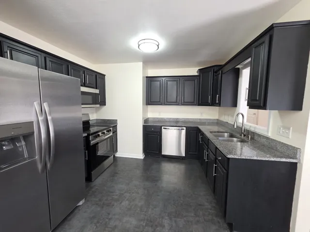 a kitchen with granite countertop a refrigerator and a sink