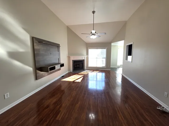 a view of a livingroom with wooden floor fireplace and windows