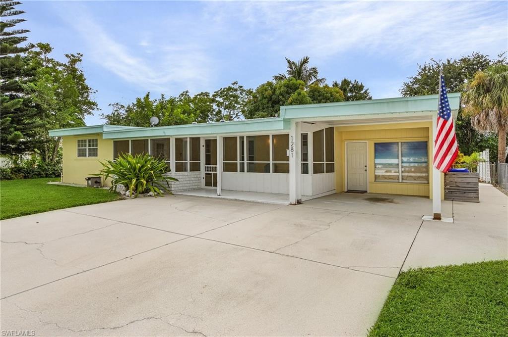 1281 10th Street North Naples, FL 34102 - Photo 2 of 31 Back of property with a sunroom and a lawn