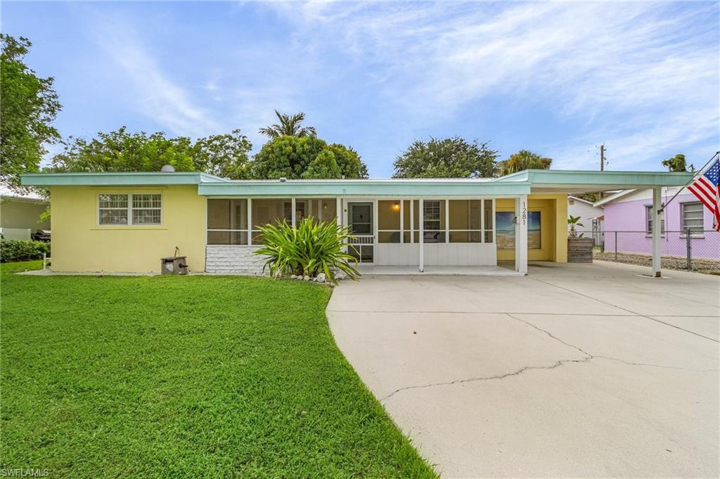1281 10th Street North Naples, FL 34102 - Photo 3 of 31 Back of property featuring a sunroom, concrete driveway, stucco siding, and a carport