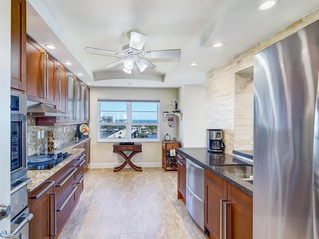 a kitchen with stainless steel appliances granite countertop a refrigerator a sink dishwasher a stove and a dining table with wooden floor