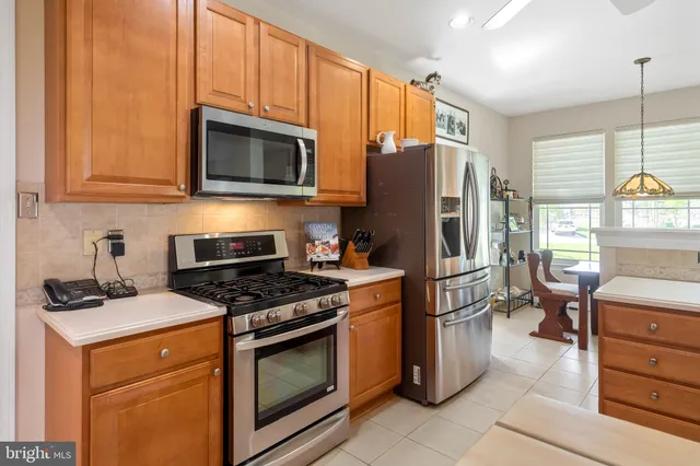 a kitchen with stainless steel appliances kitchen island granite countertop a refrigerator a stove a sink a oven with a dining table and chairs