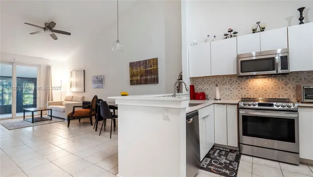 a open kitchen with stainless steel appliances a stove a sink a oven a dining table and chairs