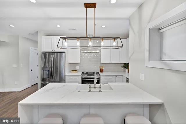 a large kitchen with kitchen island a stove a sink a dining table and chairs with wooden floor